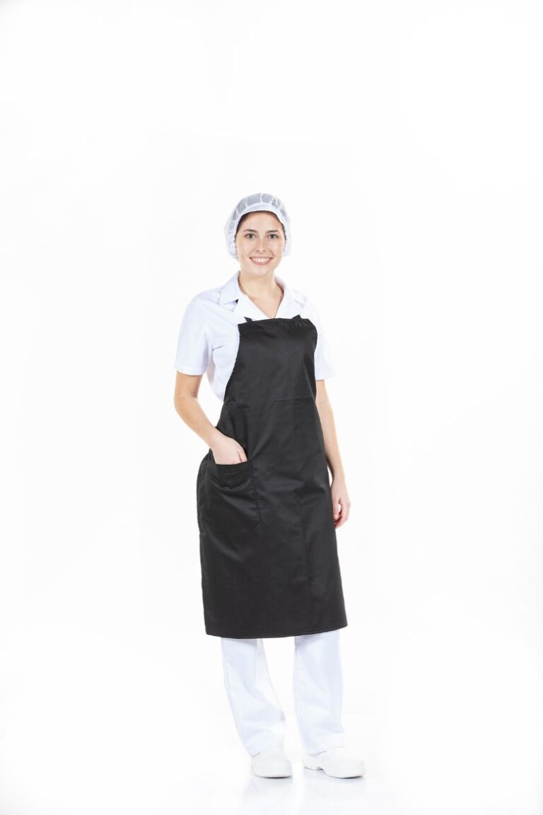 Senhora Vestida com uma calça branca, uma túnica da mesma cor e um avental de peito feminino de cor preta para ser usado como peça para uniforme profissional fabricado pela Unifardas