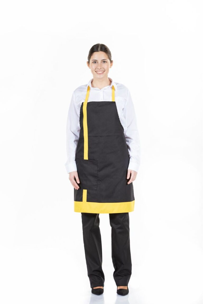 Trabalhadora da área da Hotelaria e Restauração vestida com uma camisa branca e um avental de peito preto com contraste a amarelo fabricado pela unifardas