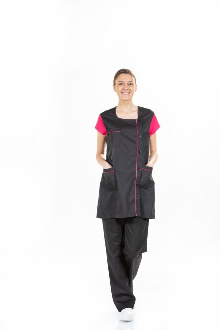 Esteticista vestida com uma bata para uniforme de estética de cor preta e contraste em cor de rosa fabricada pela Unifardas
