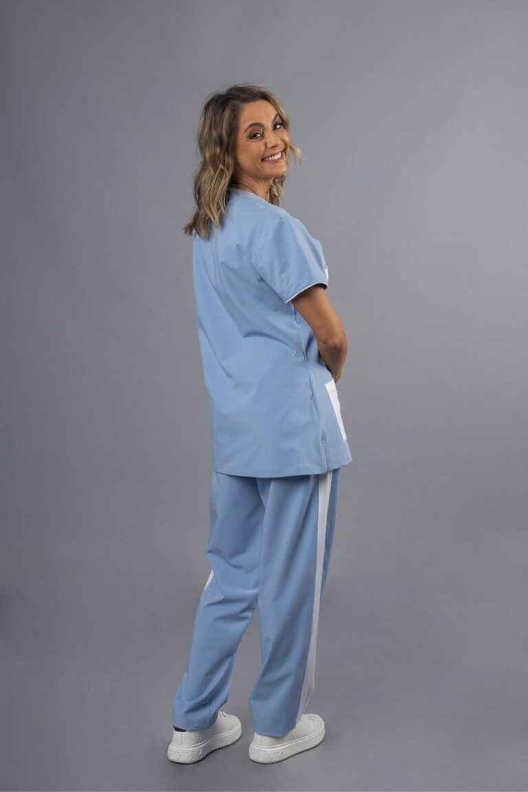 Profissional de saúde vestida com uma túnica azul e uma calça hospitalar feminina azul com tiras brancas nas laterais, para serem usadas como peça de farda de trabalho