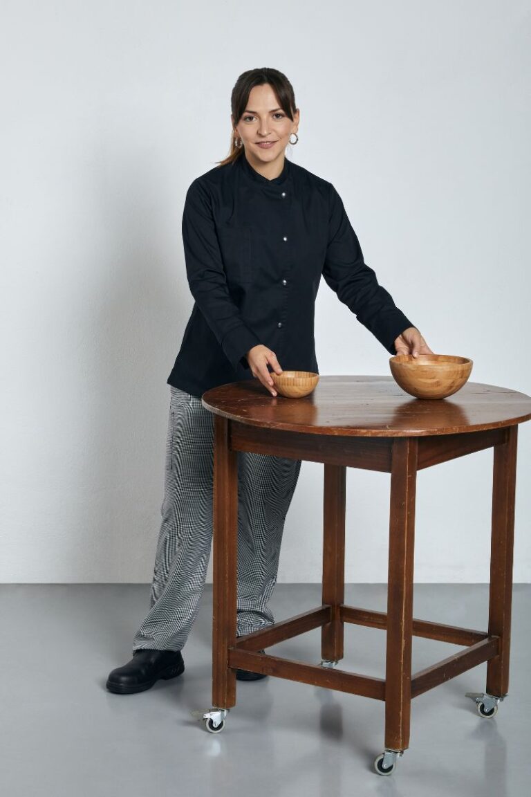 Senhora vestida com Jaleca Feminina Preta para ser usada como Uniforme de Cozinha fabricado pela Unifardas
