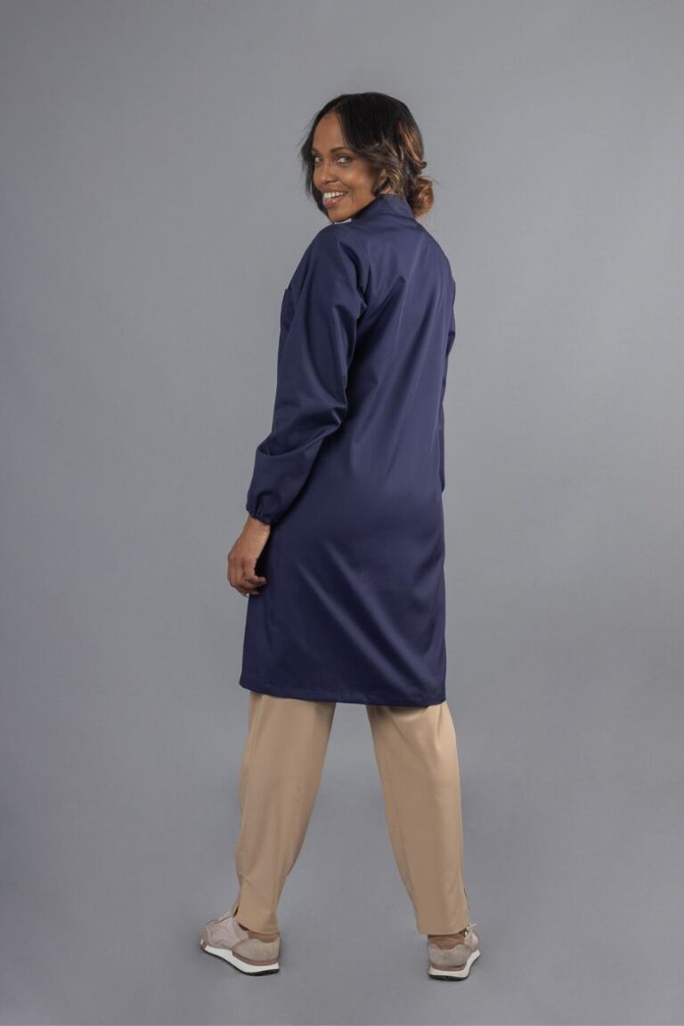 Senhora vestida com uma bata de trabalho feminina da cor azul marinha para ser usada como peça de roupa de trabalho fabricada pela Unifardas